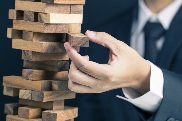 Man in suit pulling block out of Jenga tower