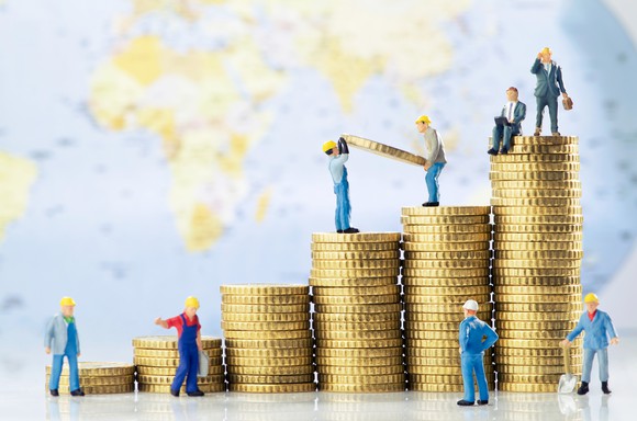 Toy workers stacking successively larger piles of coins, symbolizing growth.